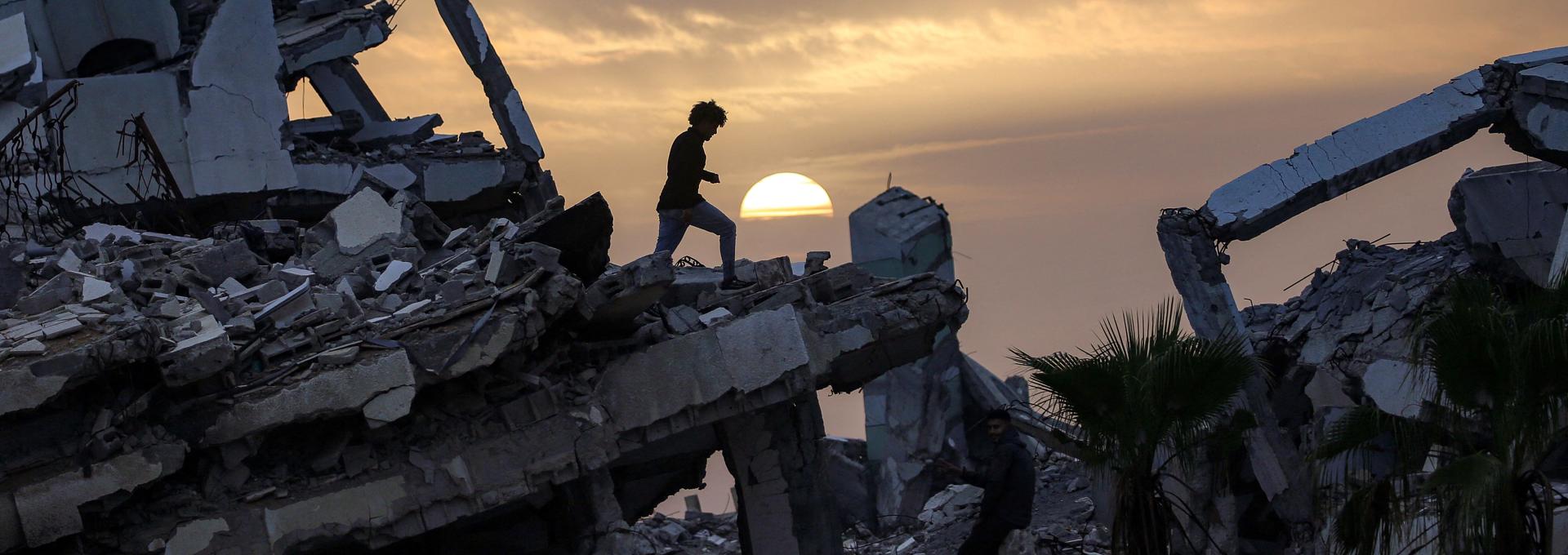 A youth walks along the ruins of a destroyed building in the Zahra neighbourhood, southwest of Nuseirat in the central Gaza Strip