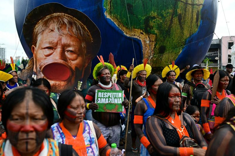 An Indigenous man holds a sign demanding respect for the Amazon